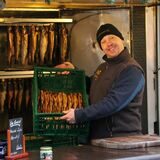 Ein Händler bietet geräucherten Fisch an.
