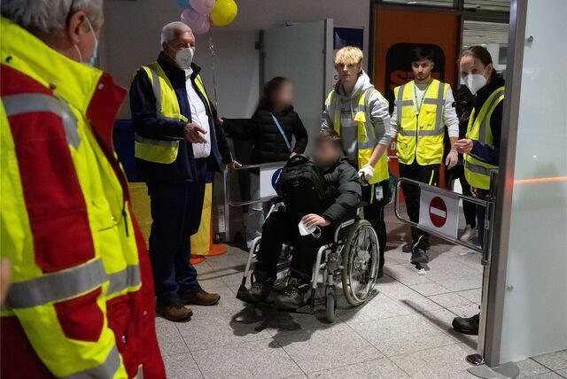 Helfer begleiten einen im Krieg in der Ukraine verletzten Jungen am Dortmunder Flughafen.