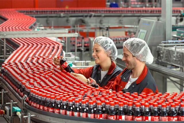 Zwei Frauen kontrollieren am Fließband Coca-Cola-Flaschen