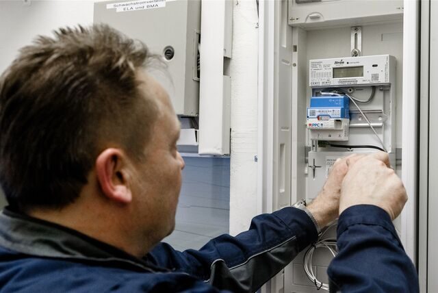 Ein Handwerker montiert an einem Stromzählerkasten