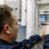 Ein Handwerker montiert an einem Stromzählerkasten