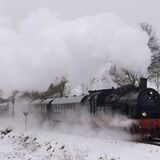 Eine schwarze Dampflokomotive fährt durch eine Schneelandschaft im Sauerland