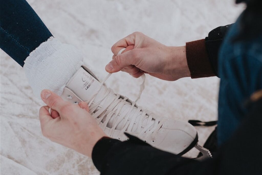 ein schlittschuh der gerade von jemand anderem geschnürt wird