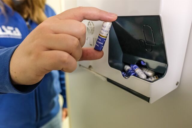 Eine Frau nimmt sich einen Tampon aus einem an der Wand angebrachten Automaten für Hygieneartikel