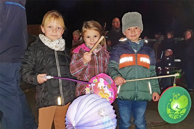 Drei Kinder halten Laternen in den Händen.