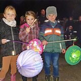 Drei Kinder halten Laternen in den Händen.