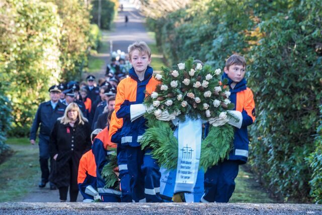 Kinder tragen einen Kranz zum Gedenken am Volkstrauertag über den Waldfriedhof Bladenhorst.