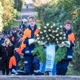 Kinder tragen einen Kranz zum Gedenken am Volkstrauertag über den Waldfriedhof Bladenhorst.