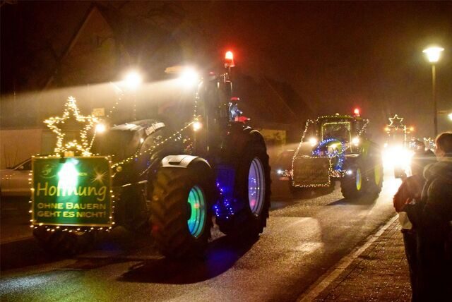 Ein Trecker ist mit bunten Lichtern geschmückt. Dahinter fahren weitere Trecker.