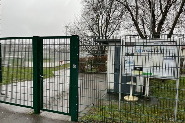 Ein Zaun rund um das Hirschkamp-Stadion in Waltrop, dahinter ist ein Schaukasten zu sehen und der Sportplatz.
