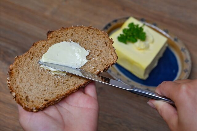 Ein Mädchen streicht Butter auf eine Scheibe Brot
