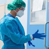 Frau legt Schutzkleidung in Krankenhaus-Flur an