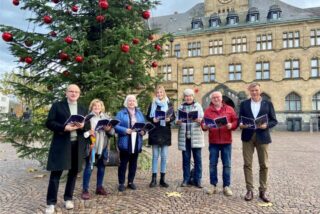 Personen stehen vor einem Weihnachtsbaum vor dem Rathaus Recklinghausen