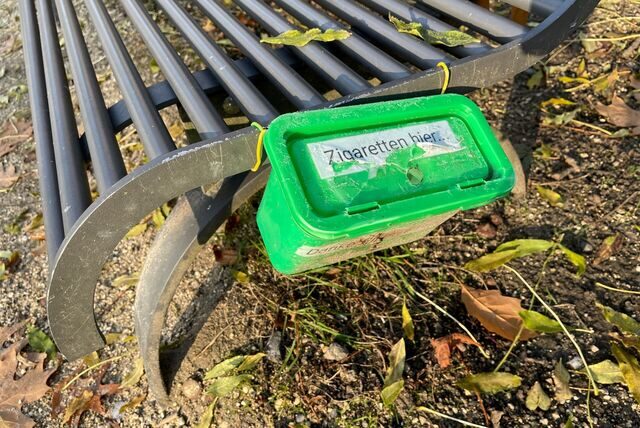 Ein selbst gebastelter Behälter für Zigarettenkippen an einer Bank im Hertener Schlosspark.