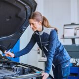 Eine TÜV-Prüferin untersucht ein Auto.