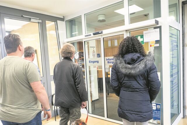 Vier Personen warten vor dem Bürgerbüro in Waltrop.