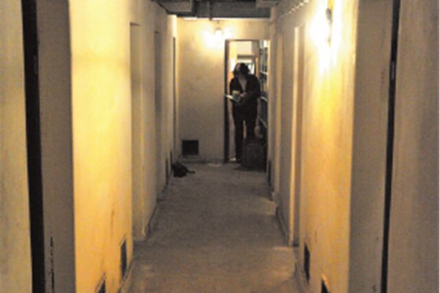 Ein Blick in einen Gang eines alten Bunkers in Waltrop, am Ende steht eine Frau und schaut in eine Unterlage.