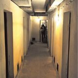 Ein Blick in einen Gang eines alten Bunkers in Waltrop, am Ende steht eine Frau und schaut in eine Unterlage.