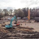 Ein Bagger und ein Kran stehen auf einer Baustelle.