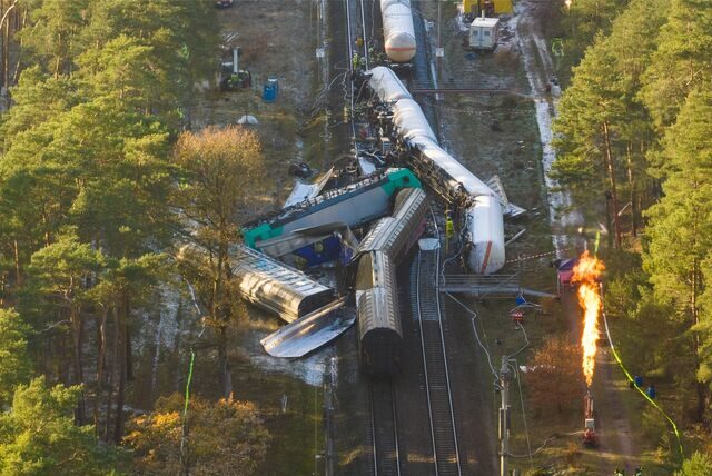 Die beschädigten Waggons liegen auf dem Bahndamm, während Spezialisten Gas aus einem der Waggons kontrolliert abfackeln.