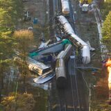 Die beschädigten Waggons liegen auf dem Bahndamm, während Spezialisten Gas aus einem der Waggons kontrolliert abfackeln.