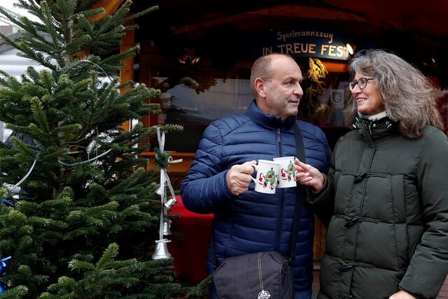 zwei Personen stehen auf dem Marktplatz und trinken Glühwein.