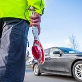 Ein Polizist hält bei einer Verkehrskontrolle eine Kelle in der Hand.