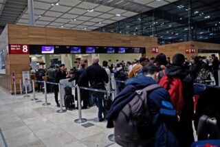 Fluggäste stehen am Flughafen BER in einer Schlange. Der Hauptstadtflughafen BER hatte zwischenzeitlich den Flugbetrieb aufgrund einer Aktion von Klimaaktivisten eingestellt. +++ dpa-Bildfunk +++