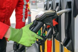 Ein Tankwart nimmt eine Zapfpistole aus der Halterung einer Zapfsäule einer Tankstelle.
