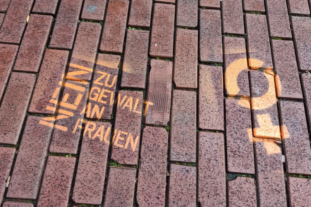 Zwei orangefarbene Graffitis auf roten Pflastersteinen Zwei orangefarbene Graffitis auf roten Pflastersteinen