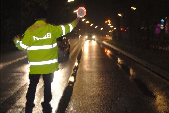 Ein Polizist mit einer roten Kelle ist auf einer Waltroper Straße von hinten zu sehen.