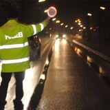 Ein Polizist mit einer roten Kelle ist auf einer Waltroper Straße von hinten zu sehen.