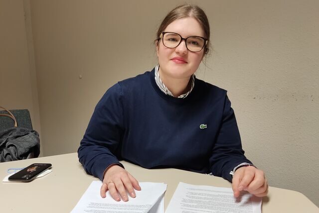 Eine junge Frau mit Brille sitzt an einem Tisch.