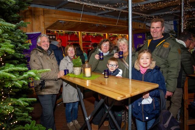 Eine Familie steht an einem Stand und trinkt Glühwein.