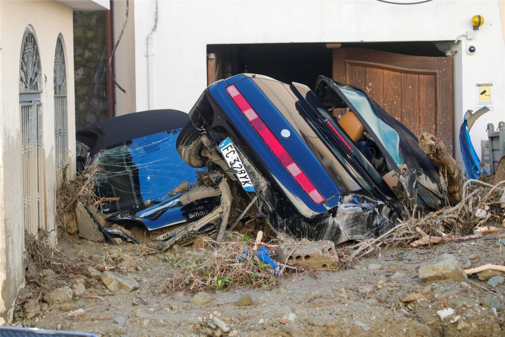 Zwei von Schlamm bedeckte Autos liegen vor einen Wohnhaus. Zwei von Schlamm bedeckte Autos liegen vor einen Wohnhaus.
