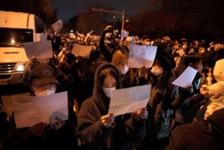 Demonstranten in Peking halten leere Papiere hoch, während sie protestieren.