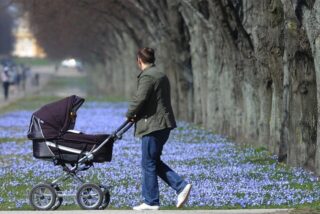 Ein Vater schiebt einen Kinderwagen in einem Park.