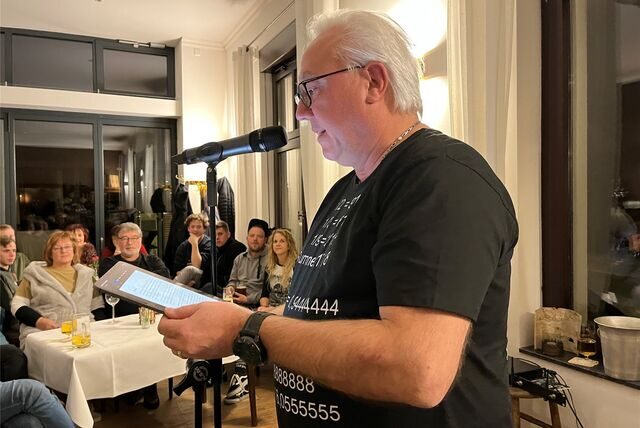 Ein Mann liest vor Publikum etwas von einem Tablet-PC vor.