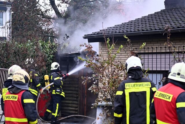Feuerwehrkräfte löschen mit einem Löschschlauch einen Brand.