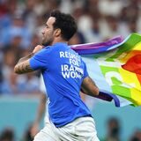 Ein Flitzer mit der Regenbogenflagge und politischen Botschaften zur Ukraine und Iran auf dem T-Shirt läuft über den Rasen.