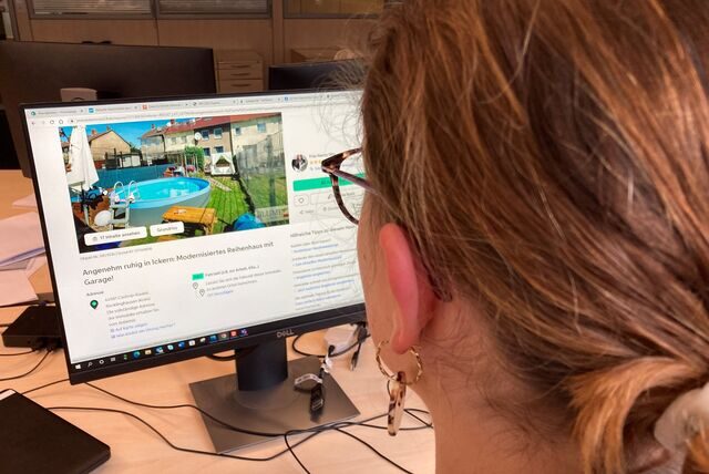 Eine Frau schaut auf eine Immobilienanzeige auf einem Computerbildschirm.
