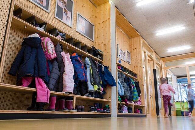 Kinder rennen in einer Kindertagesstätte einen Gang entlang.