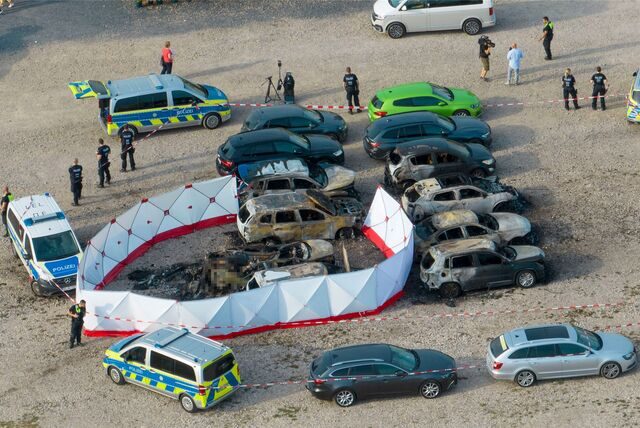 Ausgebrannte Fahrzeuge stehen nach dem Absturz eines Kleinflugzeugs an dem aufgestellten Sichtschutz, mit dem das Flugzeugwrack abgeschirmt wurde