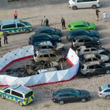 Ausgebrannte Fahrzeuge stehen nach dem Absturz eines Kleinflugzeugs an dem aufgestellten Sichtschutz, mit dem das Flugzeugwrack abgeschirmt wurde