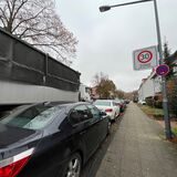 Ein Lastwagen fährt haarscharf an mehreren parkenden Autos vorbei.
