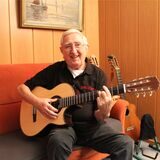 Der 91-jährige Norbert Thamm sitzt in seinem Wohnzimmer auf einem Sofa und hält eine Gitarre in der Hand.