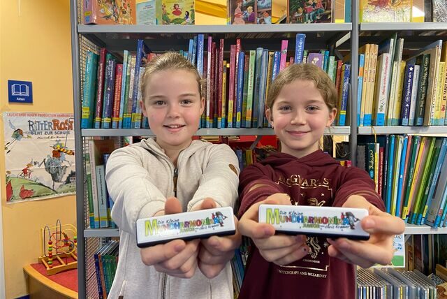 Carlotta (l.) und Annika zeigen die kleine Mundharmonika in der Stadtbücherei in Oer-Erkenschwick. Beide Mädchen besuchen die vierte Klasse der Ewaldschule.