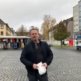 Ein Mann in schwarzer Jacke steht auf dem leeren Neumarkt in Recklinghausen-Süd während des Wochenmarktes an einem Dienstag.