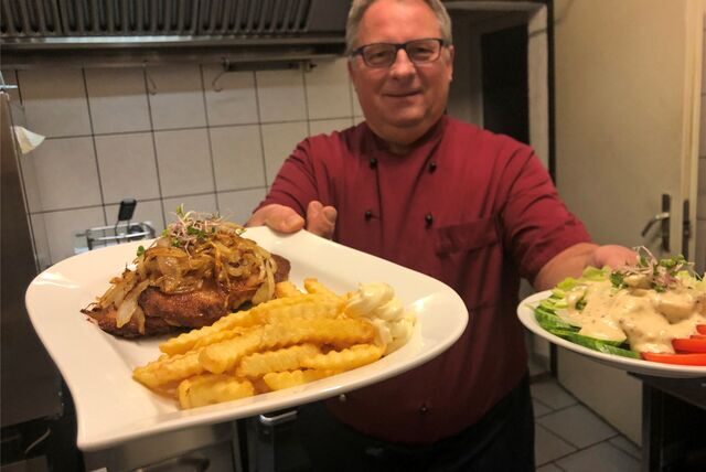 Frank Golabek serviert Zwiebelschnitzel mit Pommes und Salat.