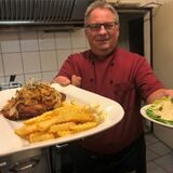 Frank Golabek serviert Zwiebelschnitzel mit Pommes und Salat.